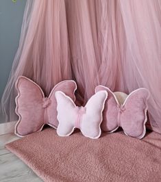 three pink pillows sitting on top of a bed