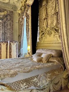 an ornate bed with gold and white decor in a fancy bedroom, complete with matching drapes