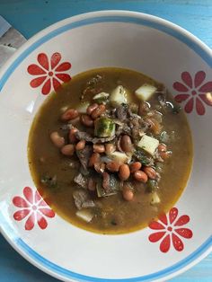 a bowl filled with soup and beans on top of a blue table