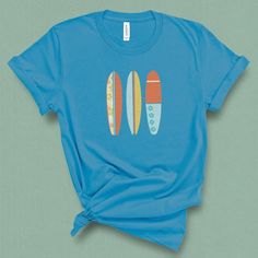 This retro summer beach surfboard t-shirt for women is for those that know surfing is a way of life. This is perfect for any summer vacation outfit. Grab this t-shirt if you are a big fan of surfing and a lover of the beach. This summer, walk down the boardwalk wearing this fun retro graphic tank top and feel some awesome beach vibes. This graphic t-shirt is for all surf lovers, surfers, and wave riders! You will look great in this surfboard t- shirt showing off your surfer spirit. DETAILS This Blue Beach T-shirt With Front Print, Casual Short Sleeve T-shirt For Water Sports, Blue Summer T-shirt For Surfing, Crew Neck Tops For Water Sports In Summer, Retro Surfing T-shirt For Beach Season, Casual Tops For Water Sports In Summer, Casual Summer Tops For Water Sports, Retro Funny Print T-shirt For Beach, Short Sleeve Graphic Print Tops For Water Sports