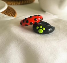 two ladybug rings sitting on top of each other in front of a cup