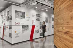 a woman is walking in front of a wall with many pictures and words on it