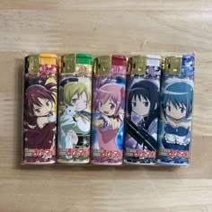 four lighters with anime characters on them sitting next to each other in front of a wooden table