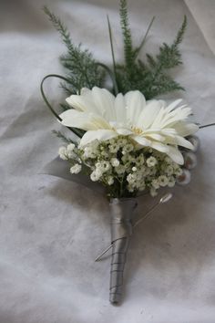 a bridal bouquet with white flowers and greenery sits on a bed linens