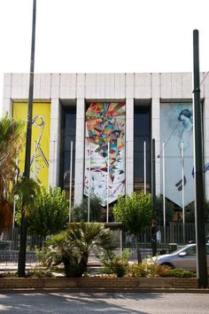 a large building with paintings on the side of it and trees in front of it