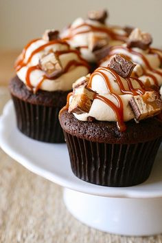 three cupcakes with chocolate frosting and caramel drizzle on top