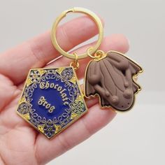 a hand holding a gold and blue keychain