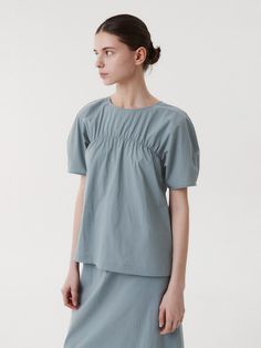 This is a clean and casual blouse by EAAH that is made out of high quality and sturdy fabric. With unique design detail and trendy mood, you can style it for your refined and casual daily outfit.- Set up matching skirt- Loop button closure on the back- High quality sea shell buttons- Shirring detail and roune neckline Gray Cotton Top For Office, Gray Cotton Office Top, Gray Relaxed Fit Cotton Blouse, Gray Cotton Short Sleeve Blouse, Gray Short Sleeve Cotton Blouse, Chic Gray Cotton Blouse, Gray Short Sleeve Blouse For Work, Gray Summer Workwear Blouse, Modern Gray Top For Spring