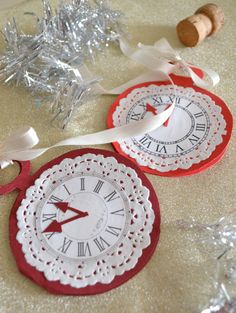 two red and white paper clocks sitting on top of a table next to silver tinsel