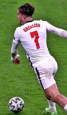 a man kicking a soccer ball on top of a field