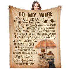 a woman holding a blanket with an image of two people under an umbrella that says to my wife you are brave