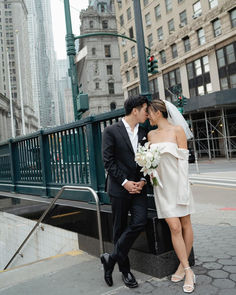 a bride and groom standing next to each other in front of a city street sign