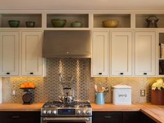 a stove top oven sitting inside of a kitchen next to wooden counter tops and white cabinets