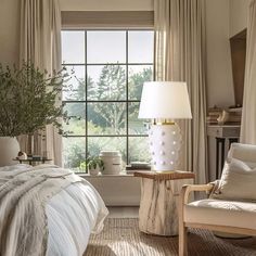 a bedroom with a bed, chair and lamp in front of a window that is open