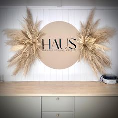 the logo for haus is displayed on a wall above a counter with dry grass