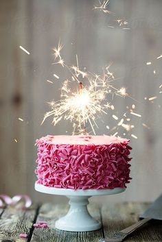 a cake with pink frosting and sparklers on top