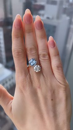 a woman's hand holding an engagement ring in front of a cityscape