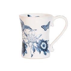 a blue and white coffee cup with flowers on the outside, butterflies flying over it