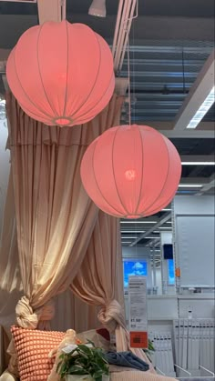 three pink lanterns hanging from the ceiling above a bed