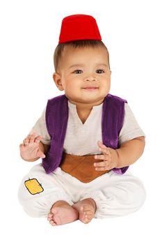 a baby sitting on the ground wearing a red hat and purple vest, smiling at the camera