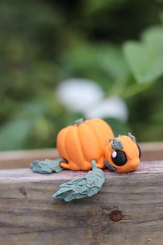 a small orange toy sitting on top of a wooden table next to leaves and flowers