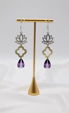 The Filigree Dangling Purple Stone Earrings are adorned with faceted fancy-cut cubic zirconia stones, elegantly set in intricate filigree designs. These stunning earrings offer a touch of vintage charm and vibrant color, perfect for adding a statement to any ensemble. Length: 2.30” Width: 0.78” Closure: Fish Hook Material: Brass with 18K Gold Plating with Rhodium Coating Lead Free and Hypoallergenic Purple Stone Earrings, Purple Earrings, Filigree Design, Purple Stones, Stunning Earrings, Fish Hook, Unique Earrings, Stone Earrings, Vintage Charms