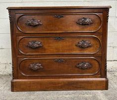 an old wooden dresser with pine cones on the top and bottom drawers, in front of a white brick wall