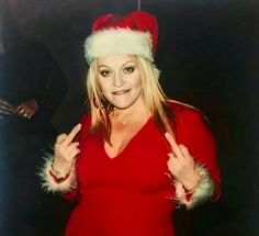 a woman wearing a santa hat giving the peace sign