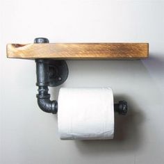 a toilet paper roll sitting on top of a wooden shelf next to a black pipe