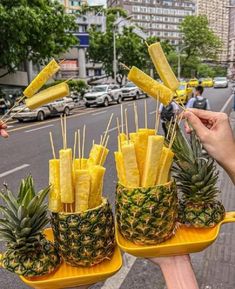 two trays filled with pineapple sticks sitting on top of a table next to a street