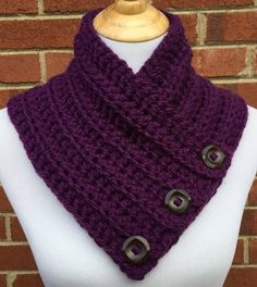 a purple knitted cowl with two metal buttons on the front and bottom, sitting on a mannequin