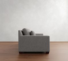 a gray couch sitting on top of a wooden floor next to a white painted wall