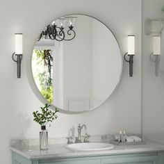 a bathroom with a large round mirror above the sink and two lights on the wall