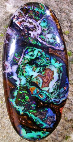 a piece of glass sitting on top of a stone floor next to a rock wall