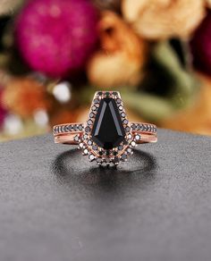 a black diamond ring sitting on top of a table with flowers in the back ground