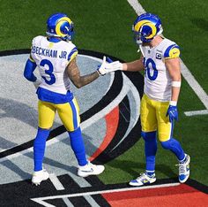 two football players standing on the field with their hands in each other's pockets