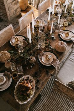 a table set for thanksgiving dinner with candles and plates