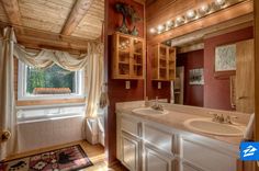 a bathroom with two sinks and a large mirror in the corner next to a window