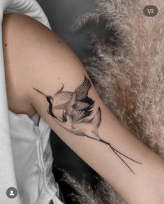 a woman's arm with a bird tattoo on it