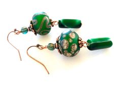 "Stunning artisan large lampwork rondelle bead earrings in Christmas green, taupe, and coppery gold accented with antique copper bead caps and ear wires. These beautiful handmade 15mm rondelles have a smooth matte finish with a slight iridescence. Slivers of glass and fine silver are used to \"draw\" the intricate designs. Beads are then fired at +900 degrees. The result is a gorgeous one of a kind lampwork bead. Beads are matched in size and color but have slightly different patterns on purpose Artisan Green Czech Glass Earrings, Green Copper Round Bead Earrings, Green Copper Bead Earrings, Lampwork Earring, Holiday Earrings, Copper Accents, Aquamarine Earrings, Christmas Green, Earrings Christmas