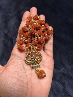 This bold and beautiful Shiva Trident pendant comes on an rudraksh mala gold cap. This is a beautiful way to celebrate your divine masculine energy whatever your gender, and is a beautiful gift for adorning your masculine beloved. See below for more information about this potent, tantric symbol and its meaning. A great gift for yogis and those studying tantra. Brass will oxidize to a more antiqued color over time. If you would like it to be bright and shiny again, just use a little bit of lemon Spiritual Locket Necklace For Navratri, Spiritual Necklaces For Puja And Festivals, Spiritual Necklaces For Navratri, Spiritual Temple Necklace With Locket For Festivals, Spiritual Necklaces For Meditation And Navratri, Spiritual Locket Temple Necklace For Festivals, Spiritual Temple Necklace For Festival Gifts, Brown Necklaces For Puja And Festivals, Festival Brown Necklace For Puja