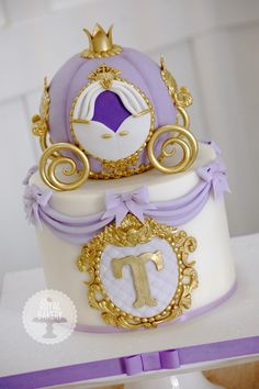 a purple and white cake with gold trimmings has a princess carriage on top