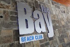 the sign for the beach club is made out of metal