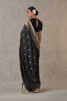 Drape yourself in elegance with this jacquard sari adorned with a Trikone and anar zari border. The sari is embellished with an embroidered border and edged with kinari, offering a touch of sophistication.