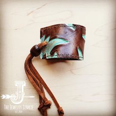 Show off your boho chic style with this women's leather cuff bracelet! This piece of genuine leather cuff jewelry features a leather strip accenting the center. This women’s cuff bracelet is handcrafted with genuine leather and hide, adding a Southern touch to your boho chic style. Wear this wide leather cuff bracelet alone or add Navajo turquoise bracelets, amazonite bracelets, and more from our bracelet bar to create your own look. Adjusts with leather ties and a wood bead that can be moved to Bohemian Turquoise Leather Cuff Bracelet, Turquoise Leather Bohemian Cuff Bracelet, Rustic Turquoise Leather Bracelet, Turquoise Hand Tooled Leather Cuff Bracelet, Turquoise Leather Cuff Bracelet Hand Tooled, Artisan Turquoise Leather Cuff Bracelet, Adjustable Hand Tooled Turquoise Cuff Bracelet, Adjustable Turquoise Hand Tooled Cuff Bracelet, Adjustable Hand-tooled Turquoise Cuff Bracelet