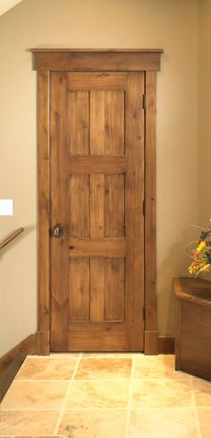 a wooden door sitting in the corner of a room next to a planter filled with flowers