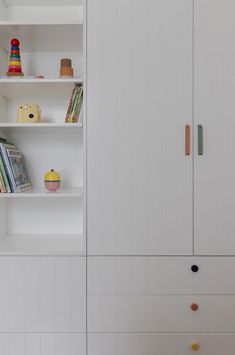 a white book shelf with books and toys on it