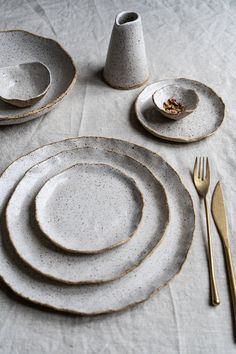 a table set with plates, silverware and a white napkin on top of it