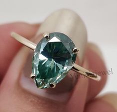 "9x6 mm Blue Green Pear Cut Moissanite Engagement Ring: A timeless solitaire design featuring a brilliant blue-green pear-cut moissanite, handmade for a personalized touch, perfect for commemorating your special moments together." ✪ ITEMS SPECIFICATION ★ Brand Name                     : Veniciajewel ★ Center Stone Use            : Moissanite ★ Main Stone Shape           : Pear Cut ★ Main Stone Color            : Blue Green (S-Z) ★ Stone Clarity                    : VVS1 ★ Total Carat Wight Engagement Gifts For Him, Engagement Ring Classic, Dainty Diamond Ring, Zierlicher Ring, Classic Engagement Rings, Birthday Gifts For Sister, Gifts For Sister, Matching Rings, Anniversary Gift For Her