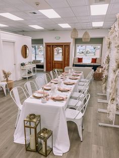 a long table is set up in the middle of a room with white chairs and tables